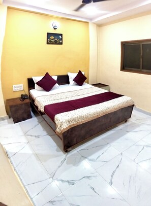 A hotel room with a bed, nightstand, and a wall-mounted light fixture.