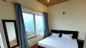 A bedroom with a bed, a ceiling fan, a window with curtains, and a view of the outdoors. - Harika Palace hidden awayfrom city chaos (Nainital)