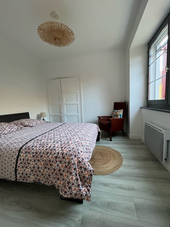 A bedroom with a bed, a chair, a window, and a radiator.
