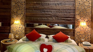 Een slaapkamer met een houten hoofdbord, een hartvormig kussen en een bedlampje.