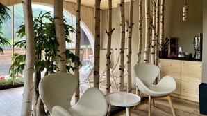 Een modern interieur met kolommen die doen denken aan berkenbomen, witte stoelen en een houten toonbank.