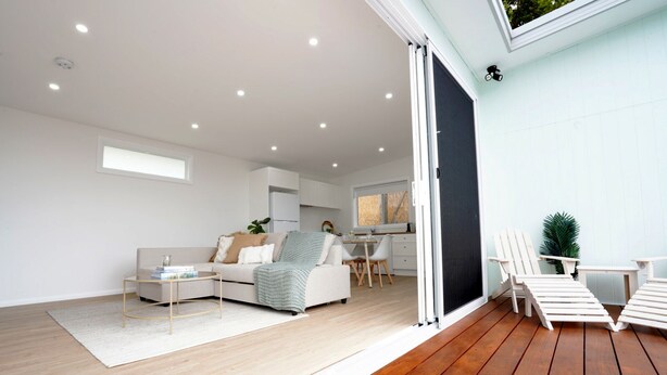 A modern living room with a sofa, coffee table, and dining area. - 5 mins walk to Beach - Modern Beachy Escape. Netflix, Full Kitchen, Comfy Beds! (Terrigal)