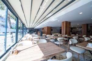 Un restaurante moderno con amplios ventanales, mesas de madera y sillas blancas.