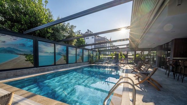 Una piscina interior moderna con agua cristalina, rodeada de sillones de descanso y una pared de vidrio con vistas panorámicas.