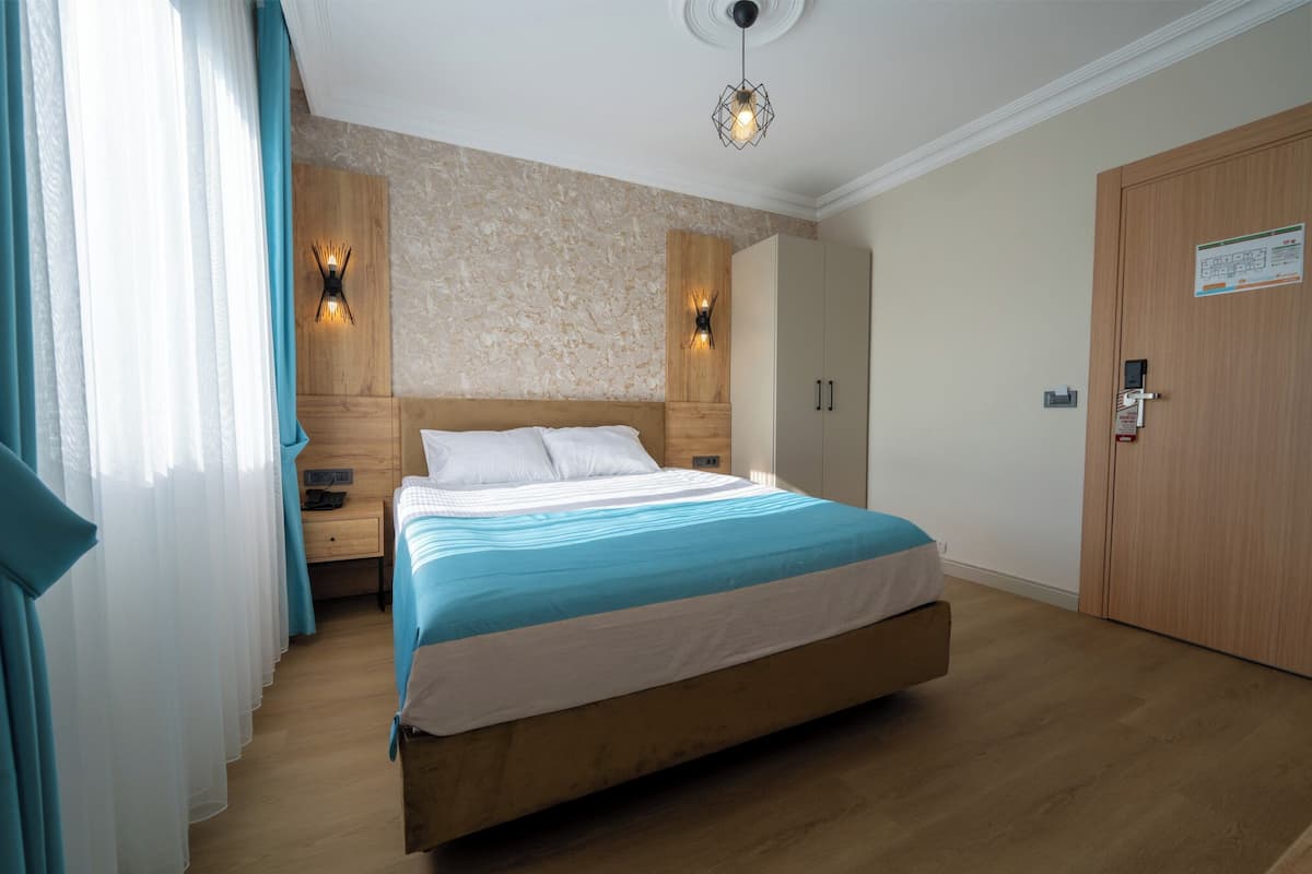 Un dormitorio con cama de madera, dos luces fijadas a la pared, un armario de madera y una puerta con un letrero.