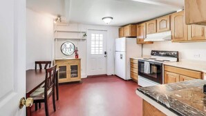 Una cocina con gabinetes de madera, un refrigerador blanco, una estufa y una mesa de comedor con sillas.