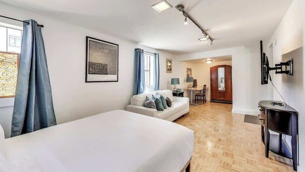 Habitación de hotel con cama, escritorio, silla, televisor y puerta que da a otra habitación.