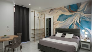 A modern bedroom with a bed, a desk, and chairs. - TH Luxury Apartment Taormina (Taormina)