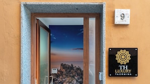 A hotel entrance with a view of a sunset over rocky terrain, a keypad door, and a sign indicating room number 9. - TH Luxury Apartment Taormina (Taormina)