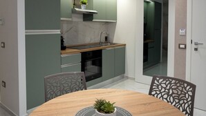 A modern kitchen with green cabinets, a marble countertop, and a built-in oven. - TH Luxury Apartment Taormina (Taormina)