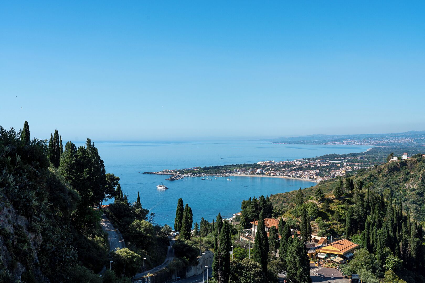 A coastal town with a view of the sea, buildings, and greenery.