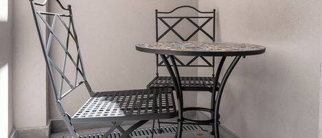 A corner with a metal table and chairs, a tiled floor, and a plain wall.