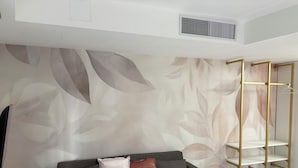 A modern living room with a grey sofa, decorative cushions, a patterned wall, and a gold-framed shelving unit. - TH Luxury Apartment Taormina (Taormina)