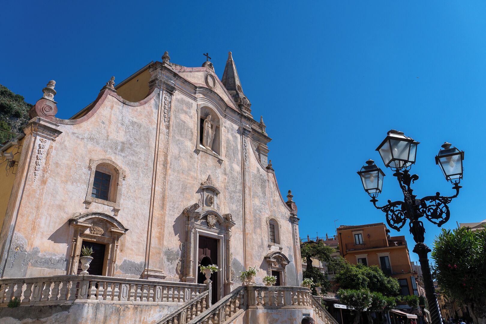 A historic building with a prominent entrance, a staircase leading to the entrance, and a street lamp nearby.
