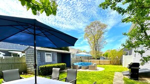 Een achtertuin met een patio tafel, stoelen en een blauwe parasol.