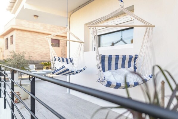 Two hammocks with striped cushions on an outdoor balcony.