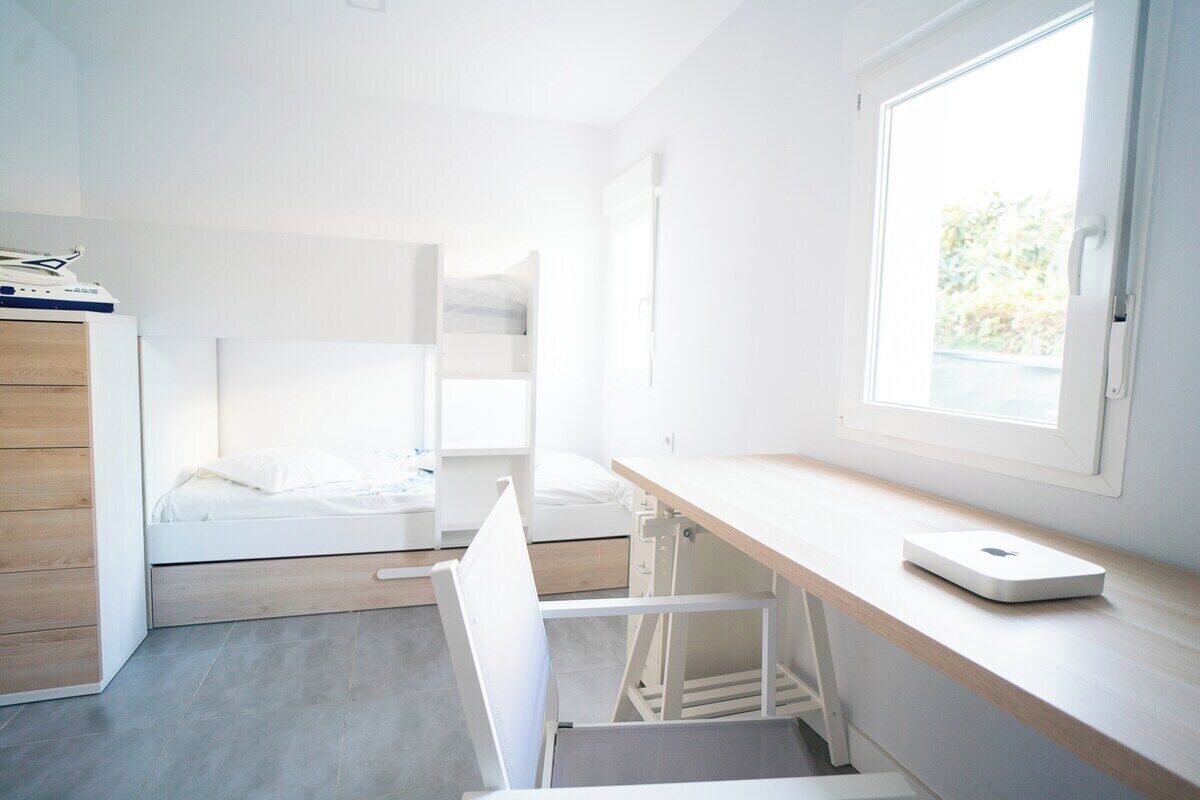 A compact, modern room with a bed, a desk, and a window.