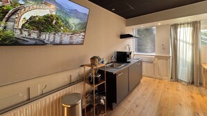 Een moderne keuken met een grote flatscreen televisie aan de muur, een RVS spoelbak en een houten aanrechtblad.