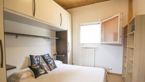 Une chambre à coucher avec un lit, une armoire, une fenêtre et un radiateur.