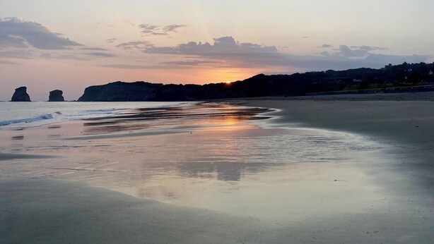 A beach with calm waters reflecting the sunset, distant rocky formations, and a clear sky. - Villa with pool, 15 min walk from the beach (Hendaye)
