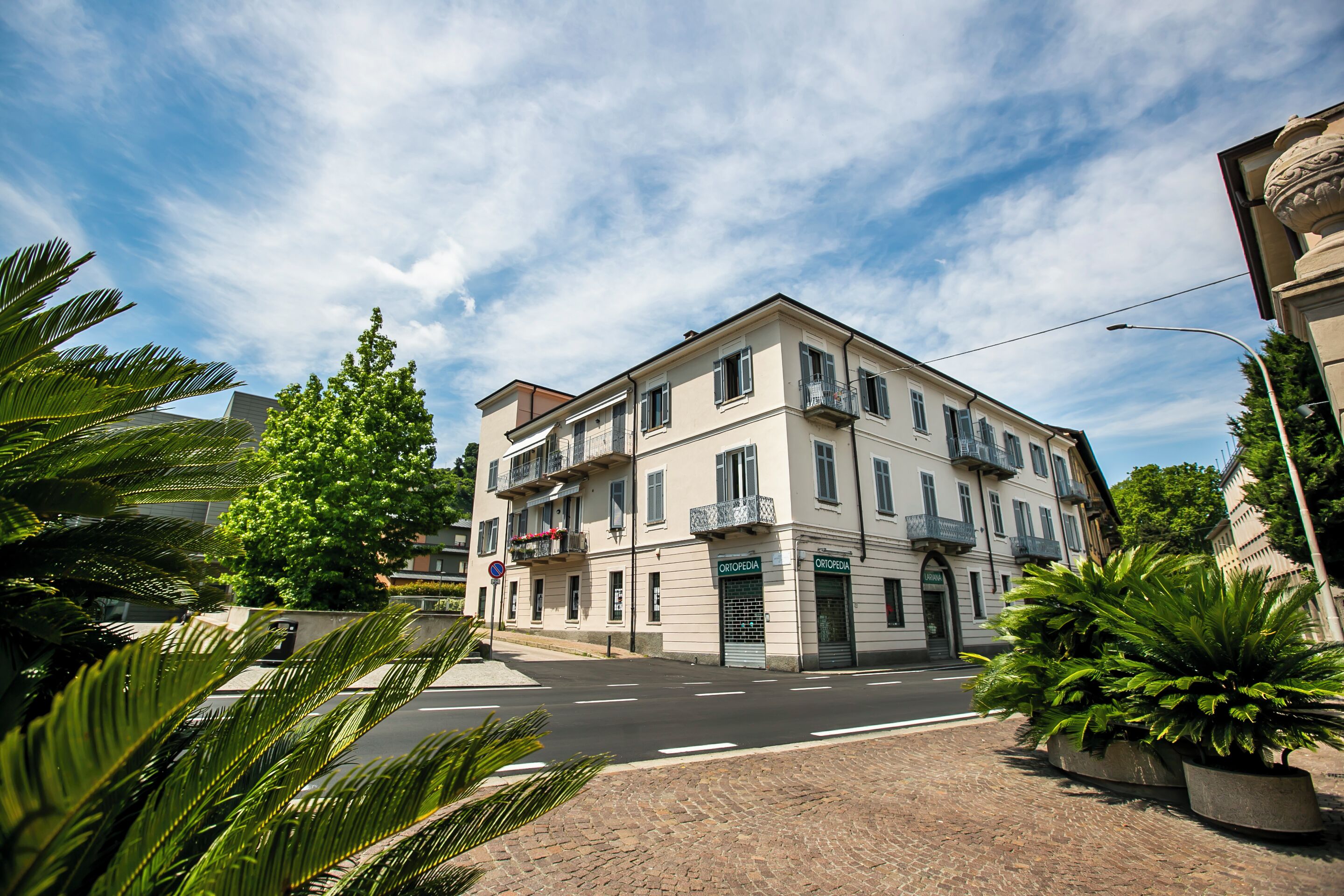 A multi-story building with a central entrance, balconies, and a clear sky.