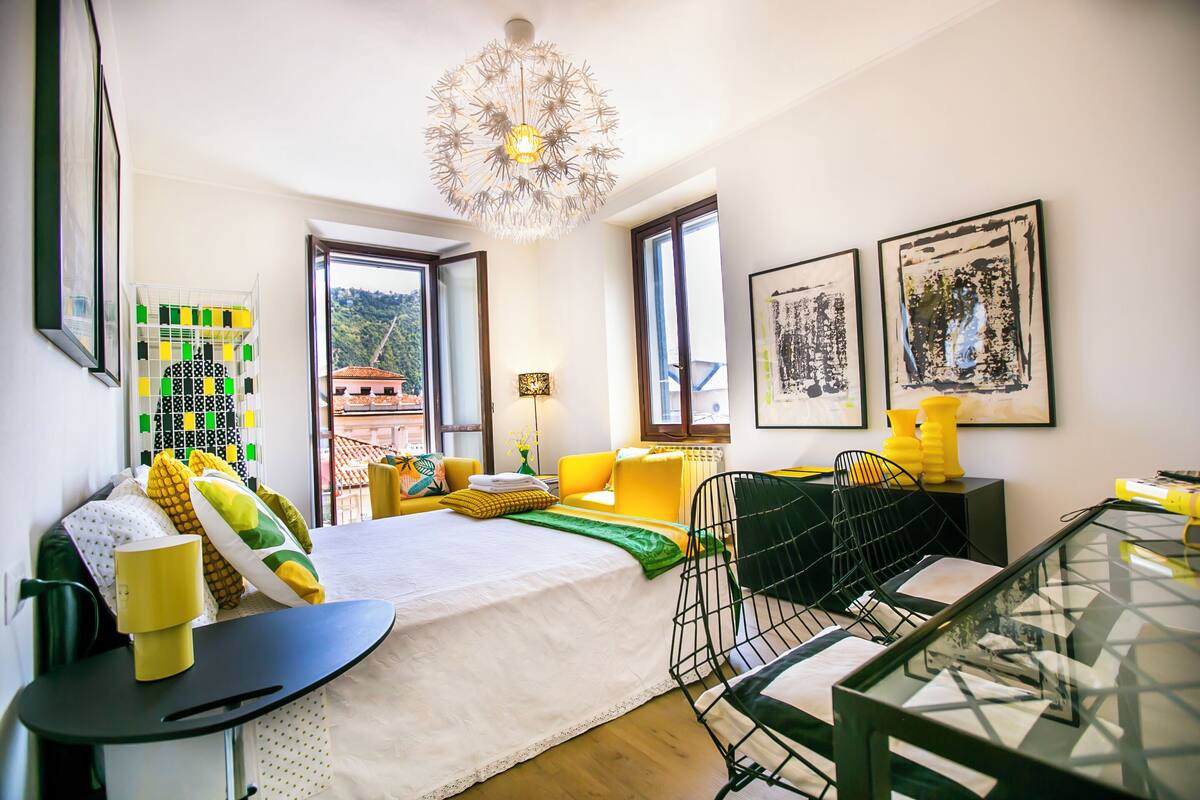Ein modernes Schlafzimmer mit einem Bett, einem Glastisch, einem Sessel und Kunstwerken an den Wänden.