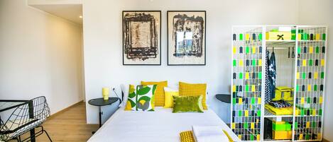 Quarto moderno com uma cama grande, um guarda-roupa com caixas organizadoras e duas pinturas abstratas na parede.
