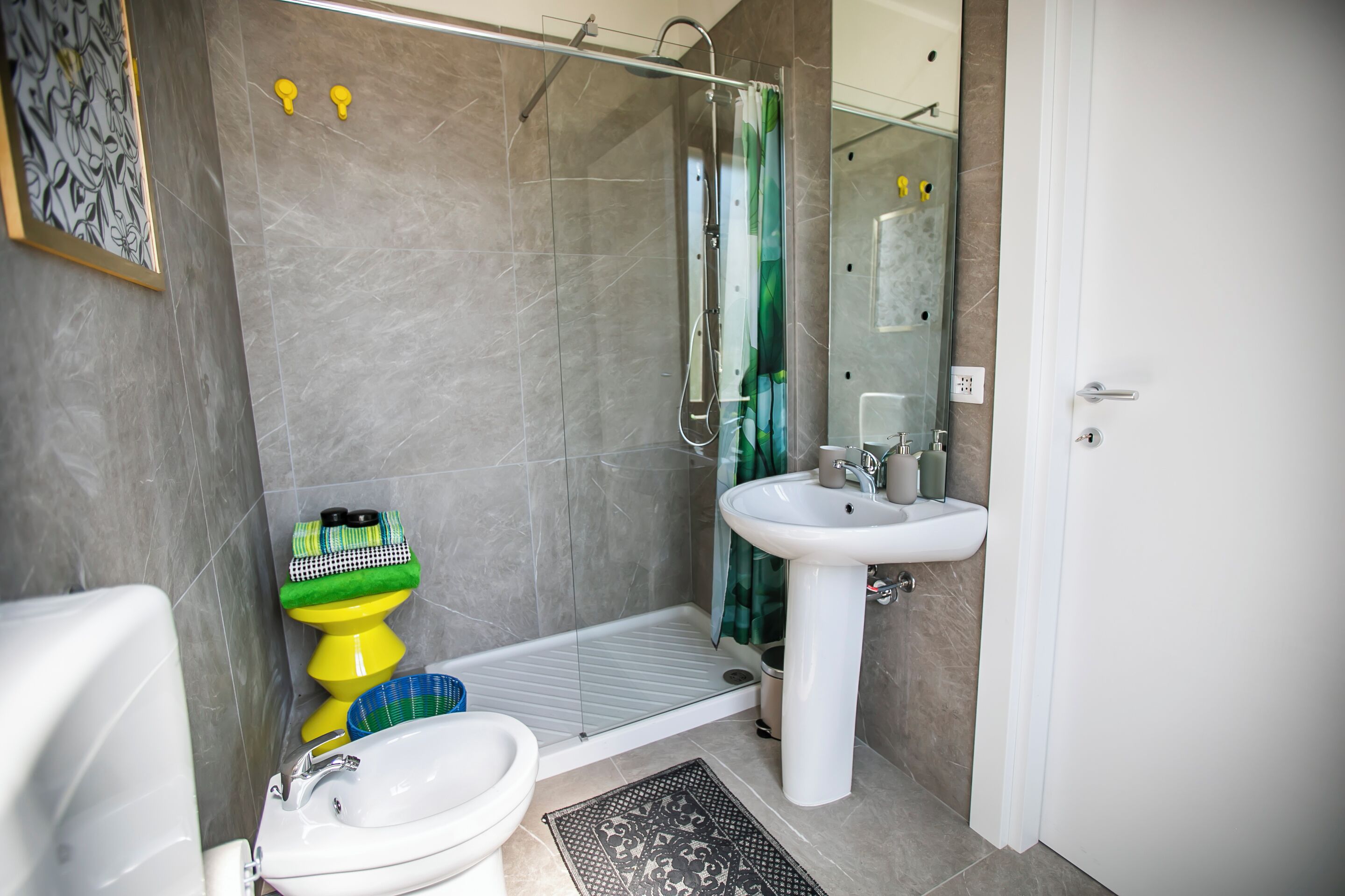 A bathroom with a shower, toilet, bidet, and sink.