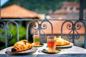 A table with croissants, a glass of tea, and a plate with a pastry.