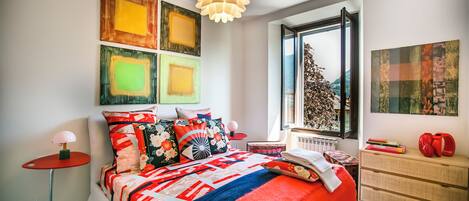 A modern bedroom with a large bed, a red lamp, and artwork on the walls.