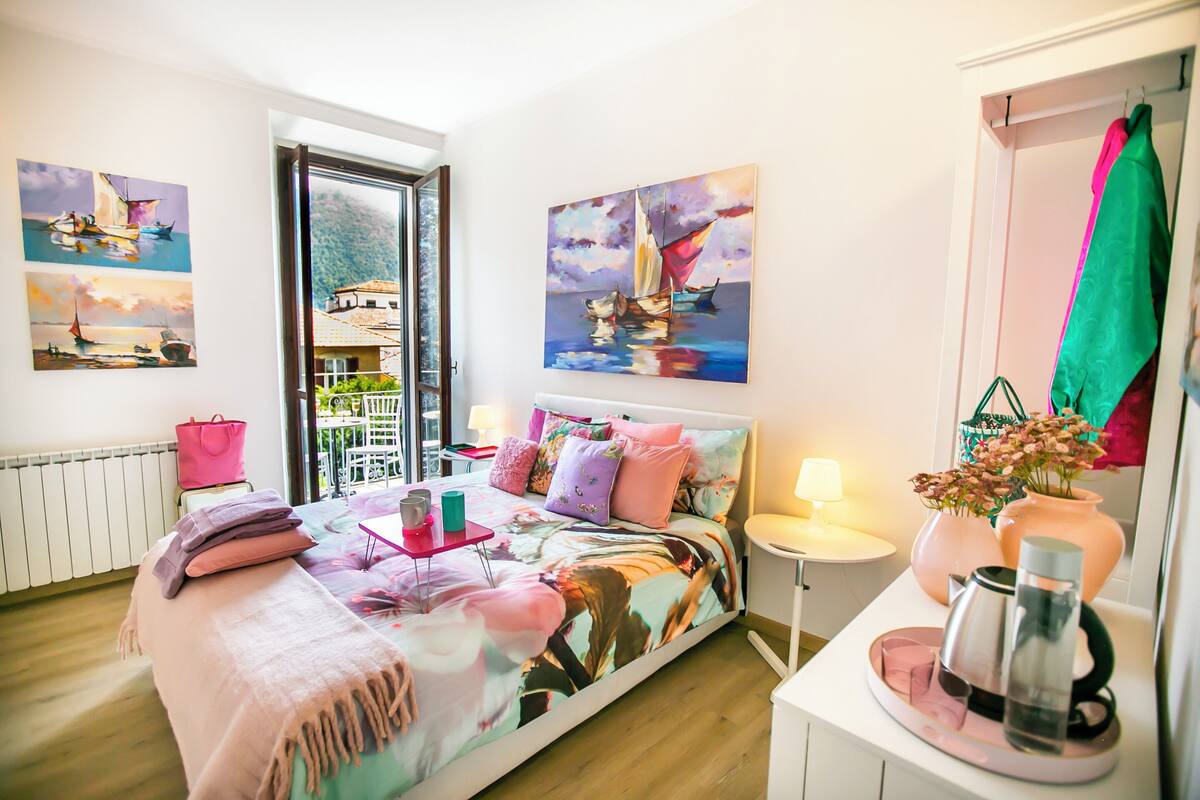 Ein Schlafzimmer mit Bett, Nachttisch und einem Fenster mit Blick auf einen Balkon.