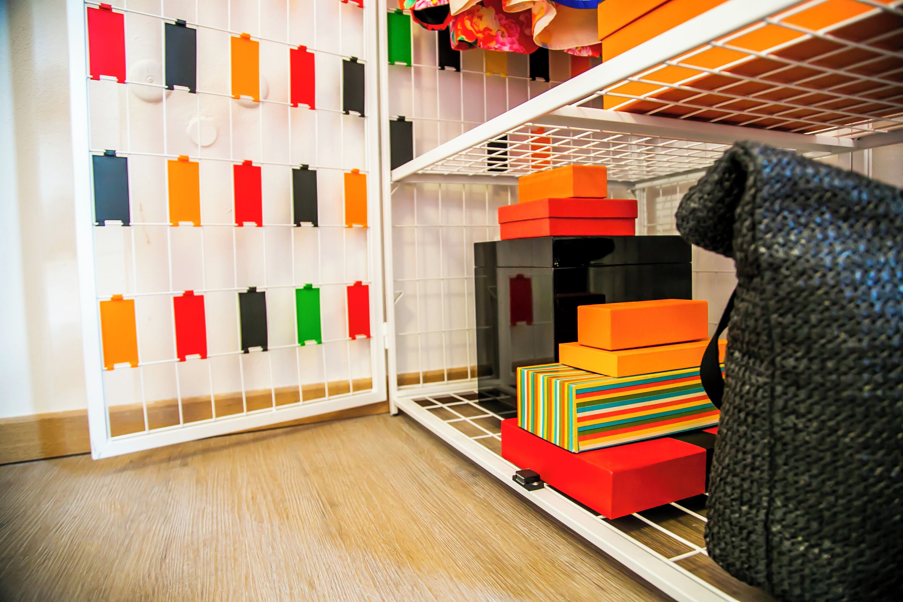 Un meuble de rangement doté de plusieurs compartiments, dont certains contiennent des boîtes de rangement colorées et d’autres des bacs de rangement noirs.