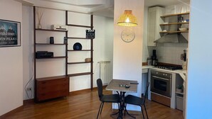 A modern kitchen with a dining area, wooden flooring, and a wall-mounted clock. - Central Boutique Apartment for2 (Roma)