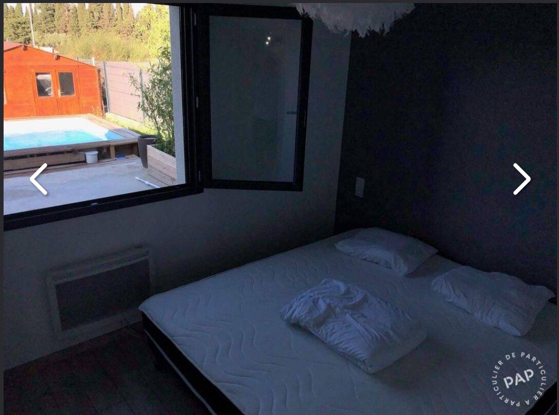 Un dormitorio con una cama individual, una ventana y vista a una piscina.