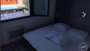 A bedroom with a single bed, a window, and a view of a swimming pool.