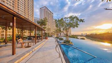 A rooftop pool area with a view of high-rise buildings and a sunset.