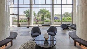 Un vestíbulo moderno con ventanas amplias, dos sillones, una mesa redonda y un sofá.