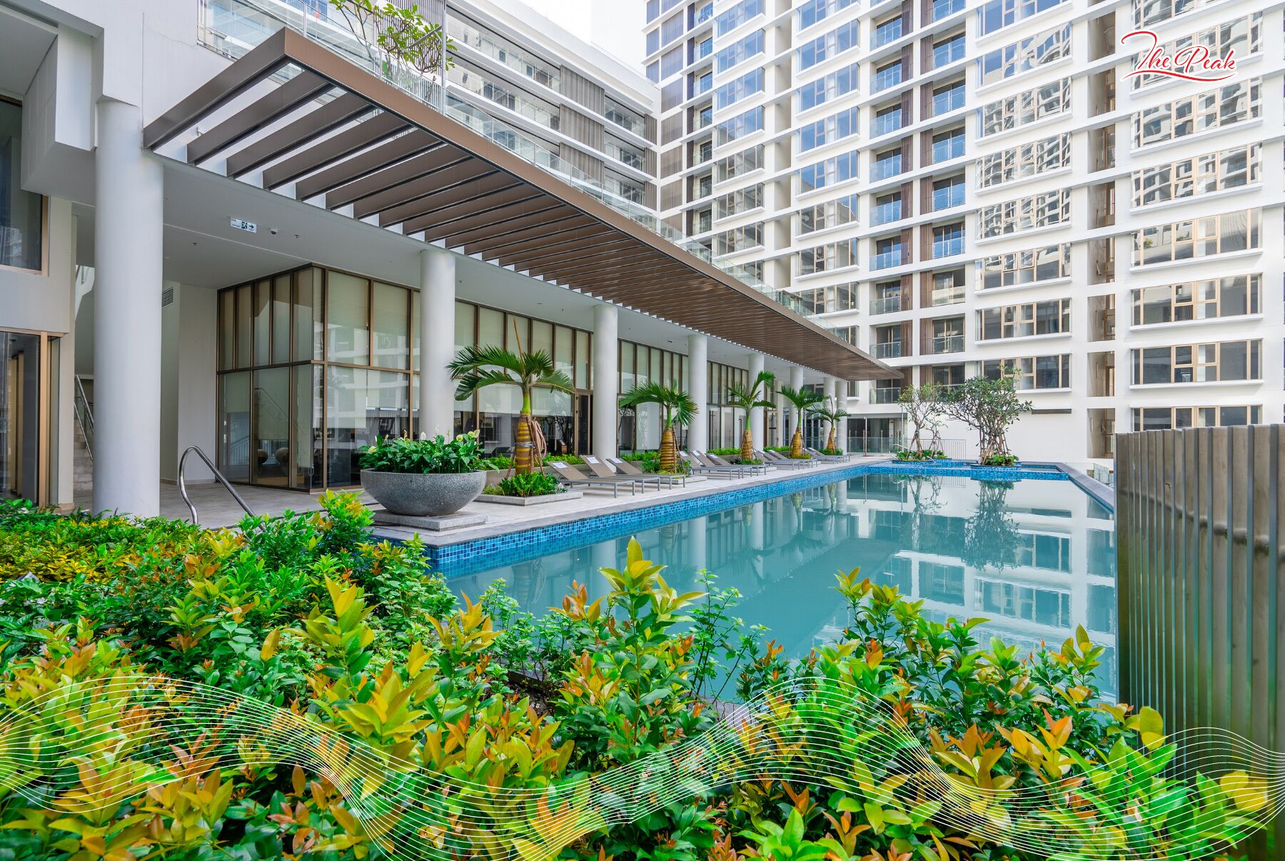 A modern hotel with a rooftop pool, surrounded by lush greenery and a covered outdoor area with seating.