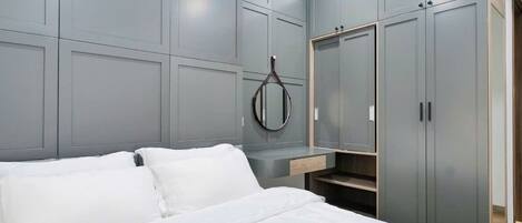 Quarto com cama, guarda-roupa cinzento e espelho.