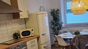 Una cocina compacta equipada con microondas, horno y comedor con mesa y sillas.