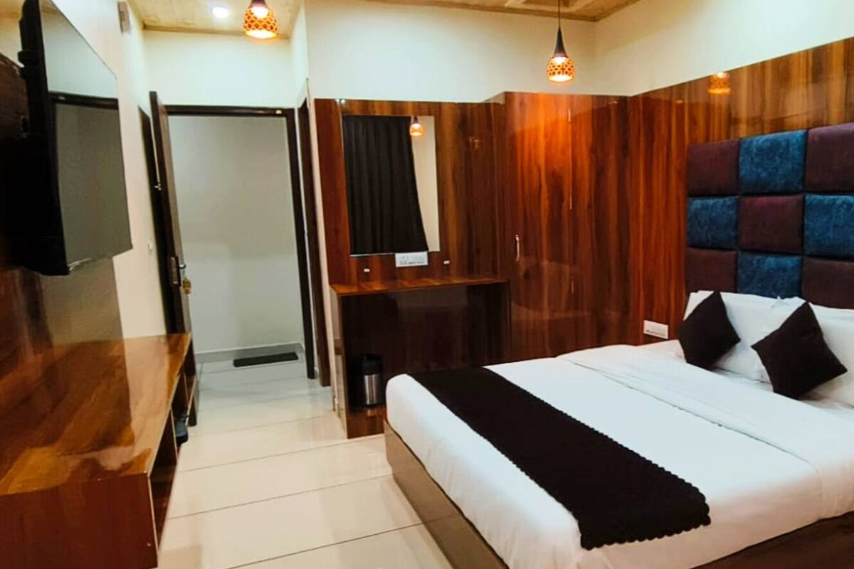 Un dormitorio con una cama grande, un cabecero de madera, un televisor y una pequeña zona de estar.