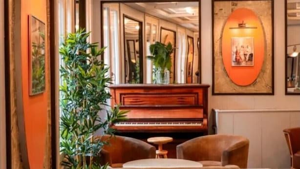 Una habitación con un piano, una mesa y sillas.