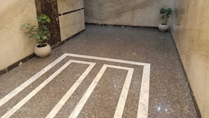 Un couloir doté d’un sol en marbre et orné d’un motif géométrique. Deux plantes en pot sont disposées de part et d’autre du couloir.