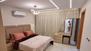 Une chambre moderne équipée d’un lit, de tables de chevet, d’un miroir et d’un appareil de climatisation.