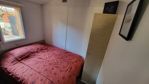 A bedroom with a bed, a wardrobe, a window, and a framed picture on the wall. - Mobil chalet (Blars)