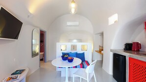 A modern kitchen with a white dining table, a built-in oven, and a red appliance.