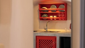 A compact kitchen with a red cabinet, a white sink, and a countertop.