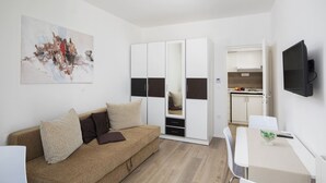 A modern living room with a brown sofa, a white table, and a kitchen in the background.