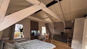 Un dormitorio de estilo loft, compacto, con cama, escritorio y kitchenette.
