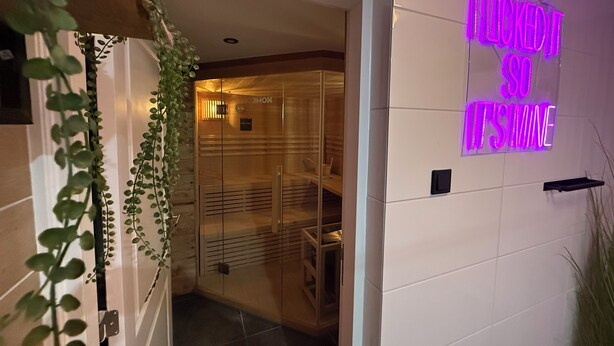 Entrada de un hotel con un letrero de neón que dice 'NICKED IT SU ITS MINE' y una puerta de cristal que da al interior.
